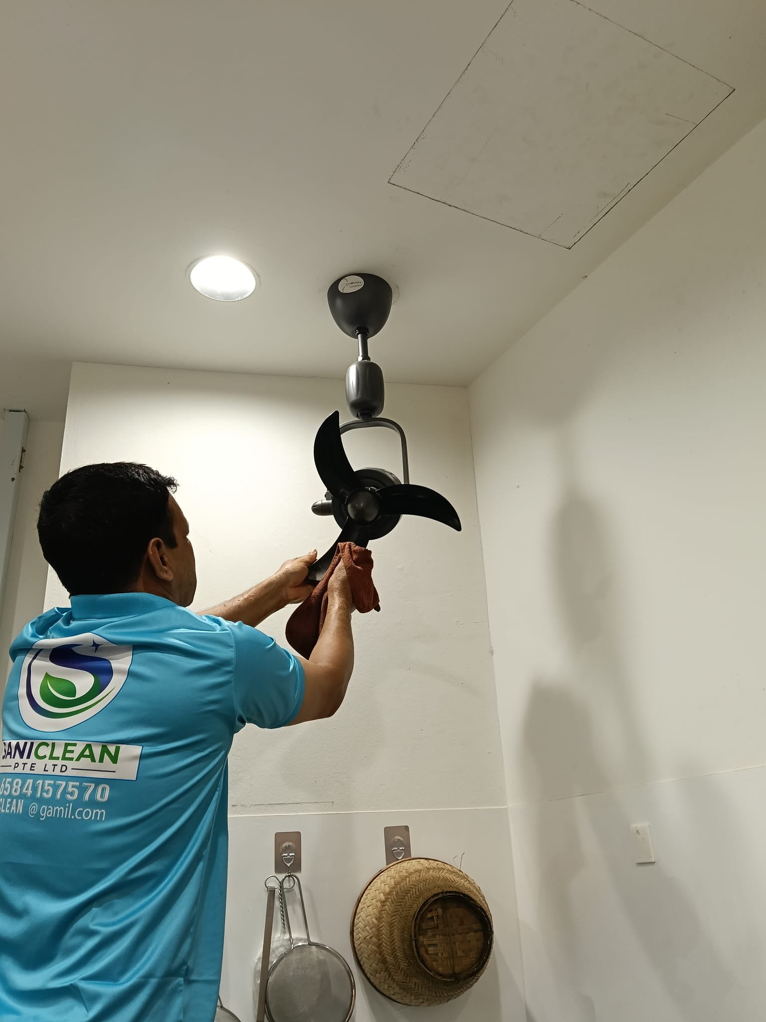 Sani Clean staff cleaning a ceiling fan fixture