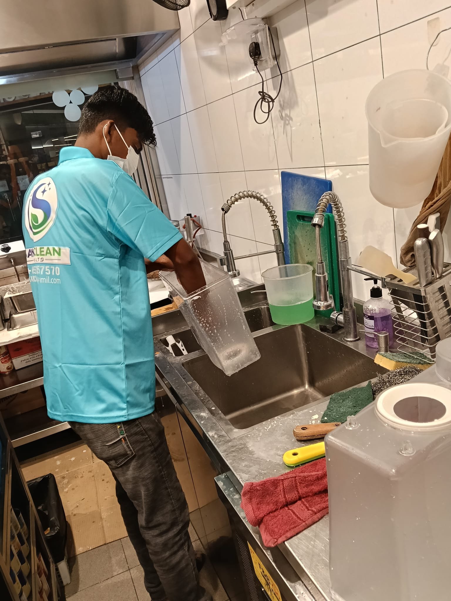 Sani Clean staff washing kitchen equipment at a sink